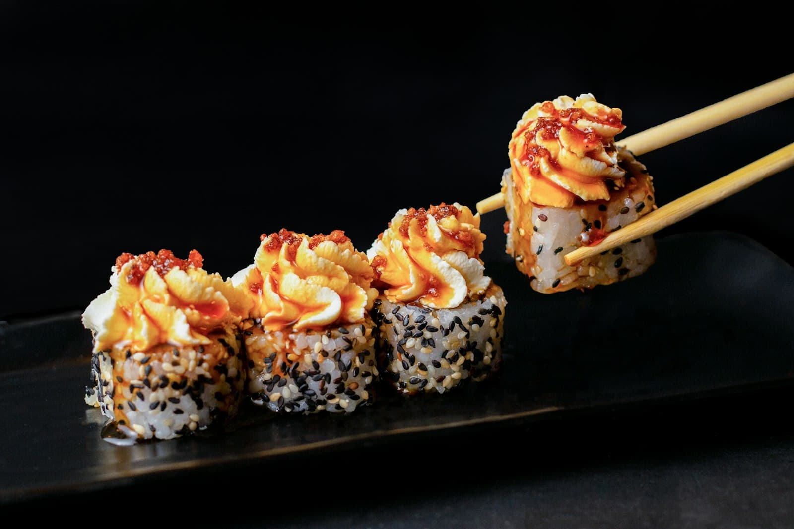 Hot rolls com gergelim e cobertura cremosa em fundo preto